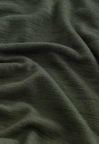 Sötétzöld, texturált anyag, amely puha kötött mintával rendelkezik, látható szálakkal és a szín, valamint a mélység finom eltéréseivel.