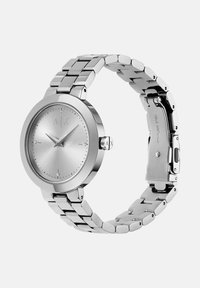 Hõbedast roostevabast terasest randmevaat, millel on ümmargune kellanägu, minimalistlik kelladial, kolm käed ja kinnitusega seotud käevõru.