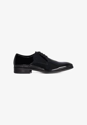 Chaussure habillée pour homme en cuir verni noir, à lacets fermés, talon bas et finition brillante sur fond blanc.