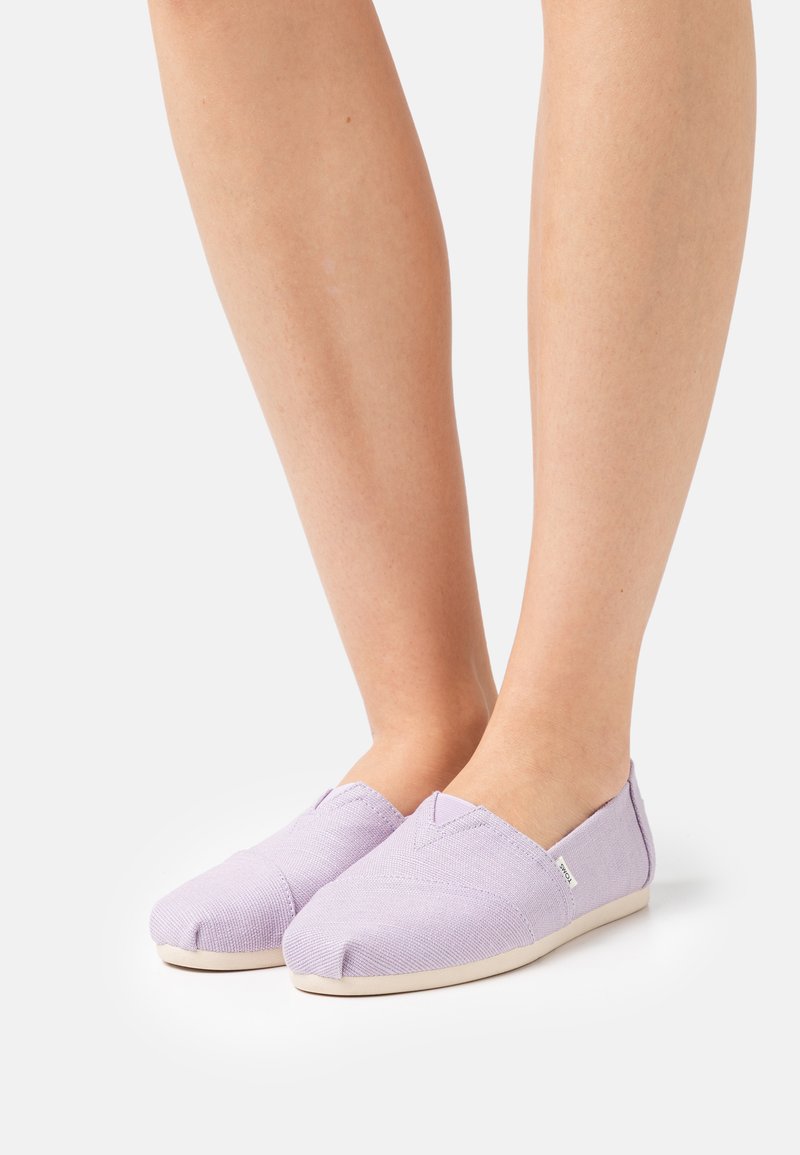 Scarpe slip-on in tela viola chiaro con punta arrotondata, tomaia testurizzata e suola in gomma beige. Presentano un design minimalista.