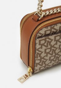 Brązowa skórzana torba ze złotymi okuciami, z wzorzystym płóciennym bokiem, zamkiem błyskawicznym i łańcuszkowym paskiem. Kompaktowy i strukturalny design.