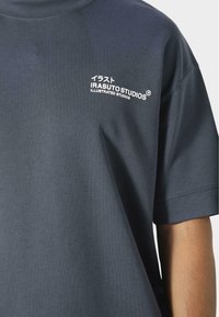 Czarna bawełniana koszulka z krótkim rękawem, okrągłym dekoltem i białym nadrukiem logo na lewej piersi z japońskim tekstem.