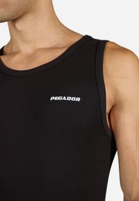 Juoda įribuota liemenė su apvaliu kaklu ir mažą baltą "PEGADOR" logotipą krūtinėje. Medžiaga atrodo minkšta ir elastinga.