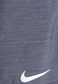 Nike sporttröja i mörkblått, tillverkad av texturerat tyg, med en vit logotyp som accent på nedre högra sidan.