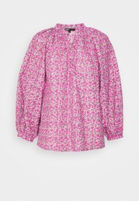 Blouse longue à manches longues à fleurs roses avec poignets froncés, léger décolleté en V et coupe ample.