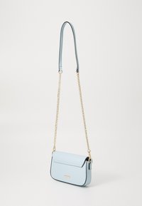 Bolso cruzado de cuero azul claro con solapa plegable, correa de cadena dorada y bordes negros en contraste. Textura suave, diseño minimalista.