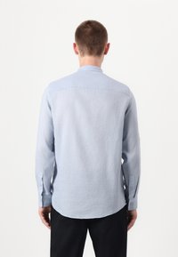 Lyseblå langermet skjorte, strukturert stoff, buet kant, enkelt lomme på baksiden, knappede mansjetter, og klassisk kragedesign.