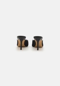 Mule-uri negre cu toc înalt, cu un superior din plasă texturată și toc negru neted. Design cu spatele deschis, având o branț bej.