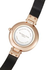 Montre ronde avec un boîtier en acier inoxydable rose gold et un bracelet en maille noire. Dispose d'un cadran blanc avec le logo "Victoria-Hyde" et un mouvement japonais.