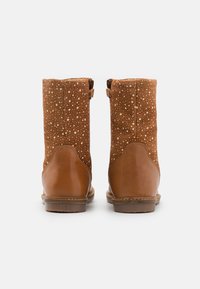 Bottes de cheville en daim marron avec un motif moucheté, accents en cuir lisse beige, fermetures éclaires sur les côtés et semelle en caoutchouc plate.