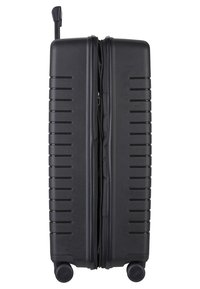 Valigia rigida nera con pannelli testurizzati, superficie liscia, doppia cerniera, manico telescopico e quattro ruote per la mobilità.