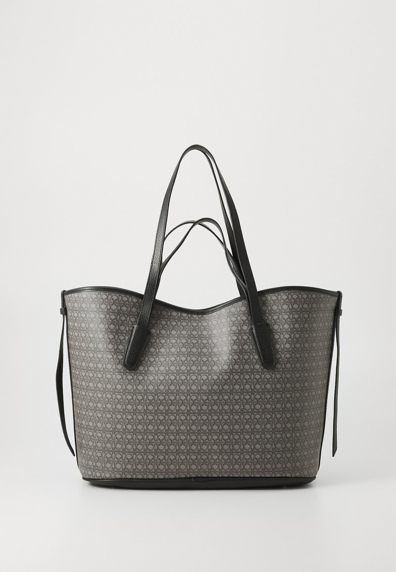 Gray patterned tote bag with a smooth texture, black leather accents, and long handles. Features a curved top and open design.