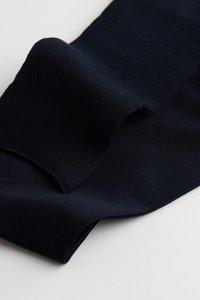 Marineblåt stof med en tekstureret overflade, der har et blødt fald og glatte kanter. Materialet virker let og fleksibelt.