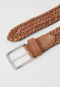 Woven hnědý semišový pásek se stříbrnou kovovou sponou. Má zapletený design a hladký kožený popruh poblíž spony.