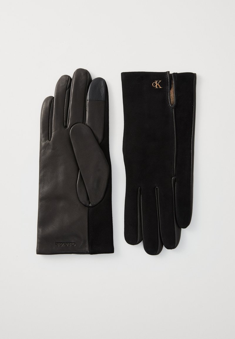 Gants en cuir noir avec des accents en suede, présentant une texture lisse, des doigts droits et un détail de logo. Design classique avec un poignet ajusté.