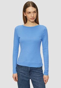 Helles blaues Langarmshirt mit Rundhalsausschnitt, aus weichem, dehnbarem Stoff, kombiniert mit dunkelblauen Jeans. Figurbetonter Schnitt.