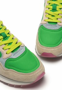 Sneaker multicolore con tomaia in tessuto e suede verde brillante, dettagli grigio chiaro e lacci giallo fluo. Suola bianca con tacco rosa.