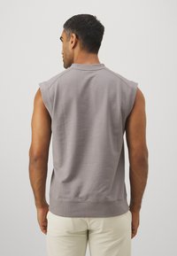 Bez rękawów szary sweatshirt z ribbowanym wykończeniem, wykonany z miękkiego materiału. Charakteryzuje się luźnym krojem i minimalistycznym designem, bez widocznych logo czy wzorów.