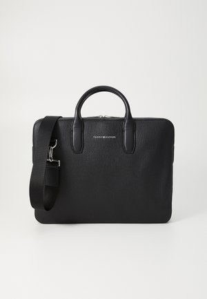 Sac à ordinateur en cuir noir avec une texture granuleuse, poignées supérieures doubles et une bandoulière ajustable. Logo en argent à l'avant.