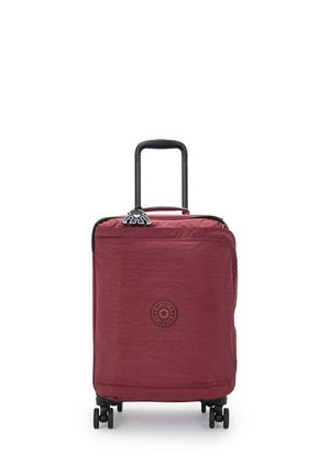 Red nylon spinner suitcase with a textured finish, black handle and wheels, featuring a circular logo on the front and zipper closure.