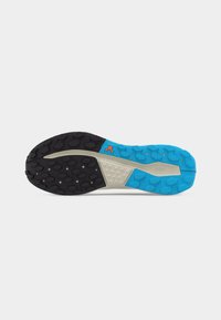 Σόλα παπουτσιού για μονοπάτια με μαύρες και μπλε ελαστικές πέλτες, μπεζ τμήμα μέσης σόλας και μικρό πορτοκαλί λογότυπο κοντά στην καμάρα.