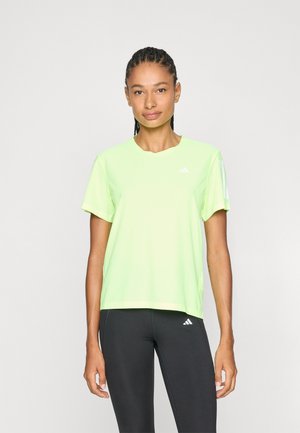 Tricou sportiv verde lime cu mâneci scurte, decolteu rotund și detalii subtile cu logo. Asortat cu colanți negri. Textură netedă.