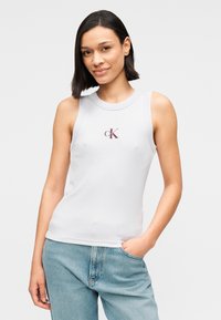 Αμάνικη λευκή μπλούζα από βαμβάκι, με στρογγυλή λαιμόκοψη και μικρό μπορντό λογότυπο στο στήθος. Κανονική εφαρμογή, με ομαλή υφή.