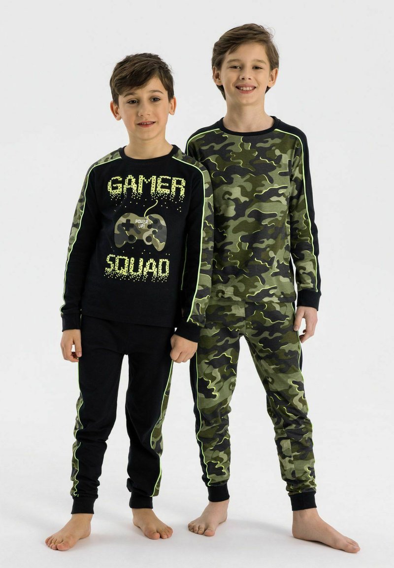 Dvaja chlapci majú na sebe rovnaké pyžamá: jedno čierne s textom "GAMER SQUAD" a grafikou herného ovládača, druhé v zelenom maskáčovom vzore.