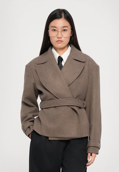 Brown wool blend wrap jacket with a belted waist, peaked lapels, and wide sleeves, paired with a white shirt and black tie.