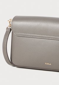 Borsa a tracolla grigia in pelle con una superficie liscia, accessori dorati e una patta ripiegabile. Caratterizzata da un logo del marchio impresso sulla parte anteriore.