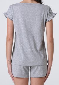 Completo da notte grigio in due pezzi realizzato in tessuto morbido, composto da una maglietta a maniche corte con dettagli arricciati e pois bianchi, abbinata a pantaloni corti coordinati.