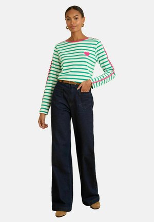 Striped long-sleeve shirt in green and white, featuring a pink heart and trim. Paired with dark blue wide-leg jeans and light brown shoes.