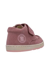 Scarpa in suede rosa con cinturino in velcro, forma arrotondata e suola beige. Presenta un logo circolare sul tallone e un design cucito.