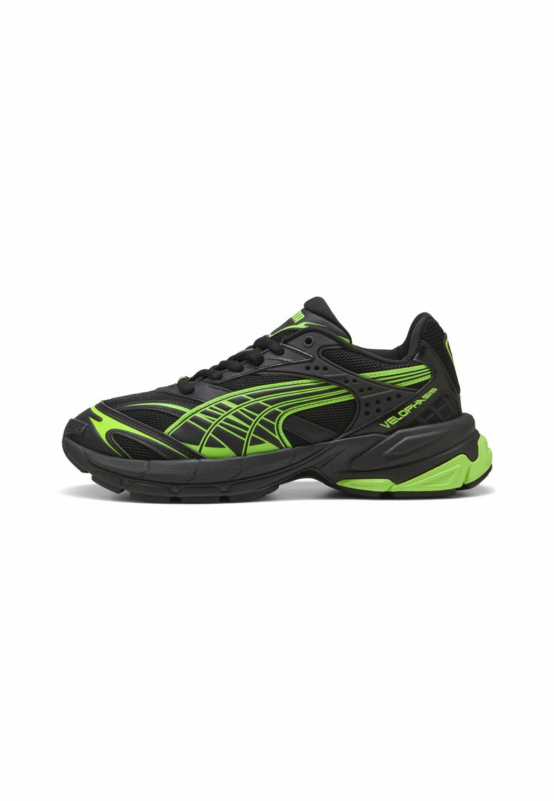 Zapatilla deportiva negra con acentos verdes, con parte superior de malla, paneles texturizados y un diseño de suela gruesa. Ligera y acolchada.