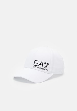Casquette de baseball blanche à visière courbée, avec logo noir "EA7 Emporio Armani" sur le panneau avant, isolée sur fond clair.