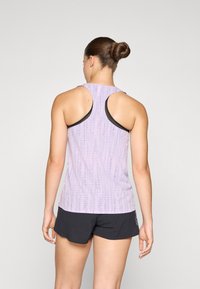 Licht paarse sporttop met een textuurpatroon, racerback ontwerp en zwarte afwerking, gecombineerd met zwarte shorts.