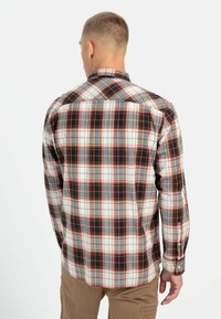Men's plaid shirt featuring a woven pattern of black, white, and orange squares; button-down collar and long sleeves with cuff buttons.