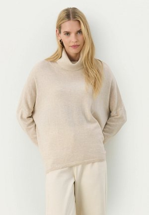 Beige turtleneck sweater made of soft fabric, featuring a relaxed fit, long sleeves, and ribbed cuffs and hem, paired with light trousers.