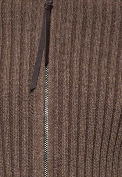 Indumento a maglia rigata marrone con chiusura a zip frontale, accentuato da un tirante in pelle. Il tessuto testurizzato aggiunge profondità e dettaglio.