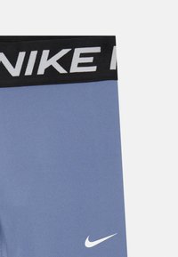 Nike leggings med svart liv som har hvit logo tekst, laget av blå elastisk materiale, med en liten svart og hvit logo på leggen.