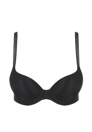 Donna in posa con reggiseno nero con ferretto e doppie spalline e slip bikini coordinati con pannello trasparente su sfondo grigio neutro.