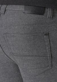 Gray woven fabric pants featuring a patch pocket, subtle texture, and a black leather label on the waistband.
