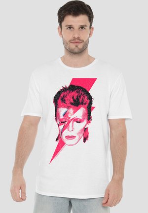 White t-shirt featuring a graphic print of a face with red and pink accents and a lightning bolt design. Short sleeves, casual fit.