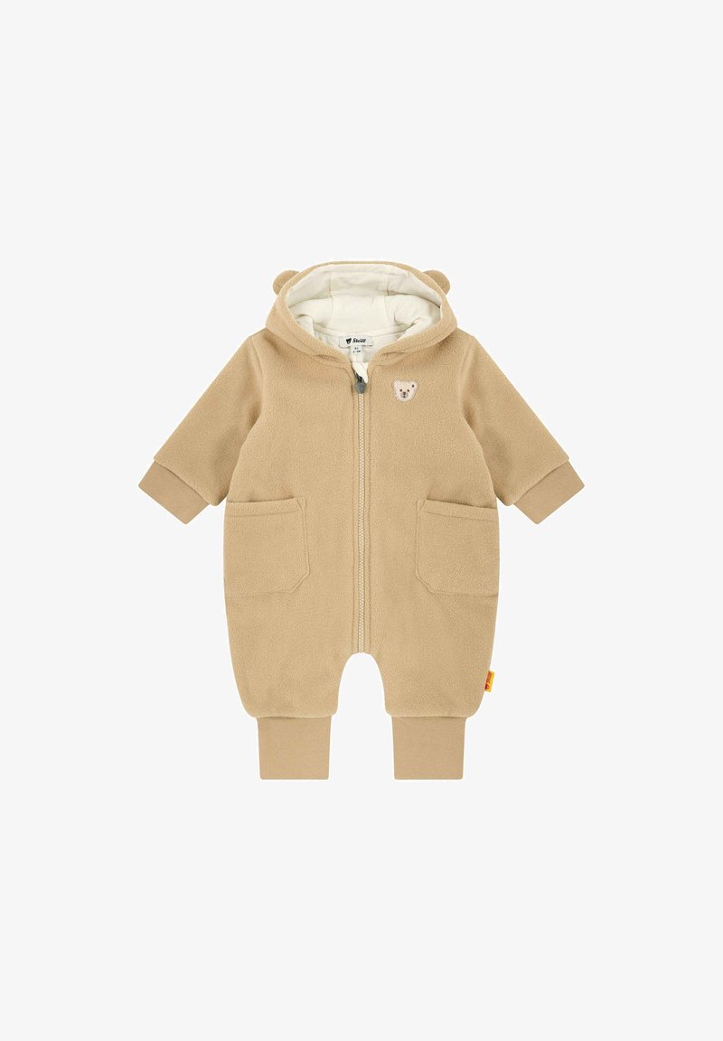 Combinaison bébé en polaire beige avec capuche, fermeture éclair devant, deux poches, poignets côtelés et petit écusson visage d'ours sur la poitrine.