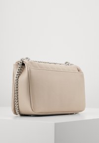 Borsa beige imbottita a forma rettangolare, con tracolla in catena argento e texture liscia. Design minimalista con dettagli di cucitura delicati.