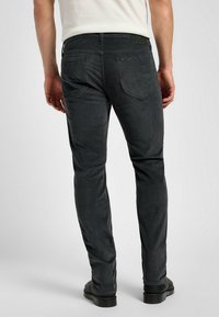 Pantaloni in corduroy grigio scuro con vestibilità slim, dotati di tasche posteriori e di una patch in pelle sulla vita. Tessuto morbido, con un sottile motivo a costine.