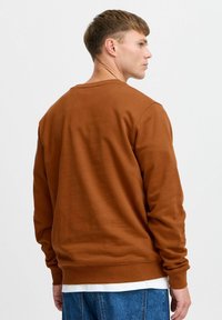 Prune sweatshirt pehmest kangast, millel on ümar kaelus, pikad varrukad ja soonikkoes mansetid. Kandmine valge särke ja teksade kohal.