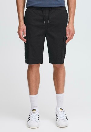 Black cargo shorts with a drawstring waist, side pockets, and a slightly textured fabric. Paired with white socks and black-striped sneakers.