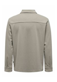 Chemise à manches longues gris clair avec col, couture visible traversant le haut du dos, et poignets aux poignets, vue de dos.