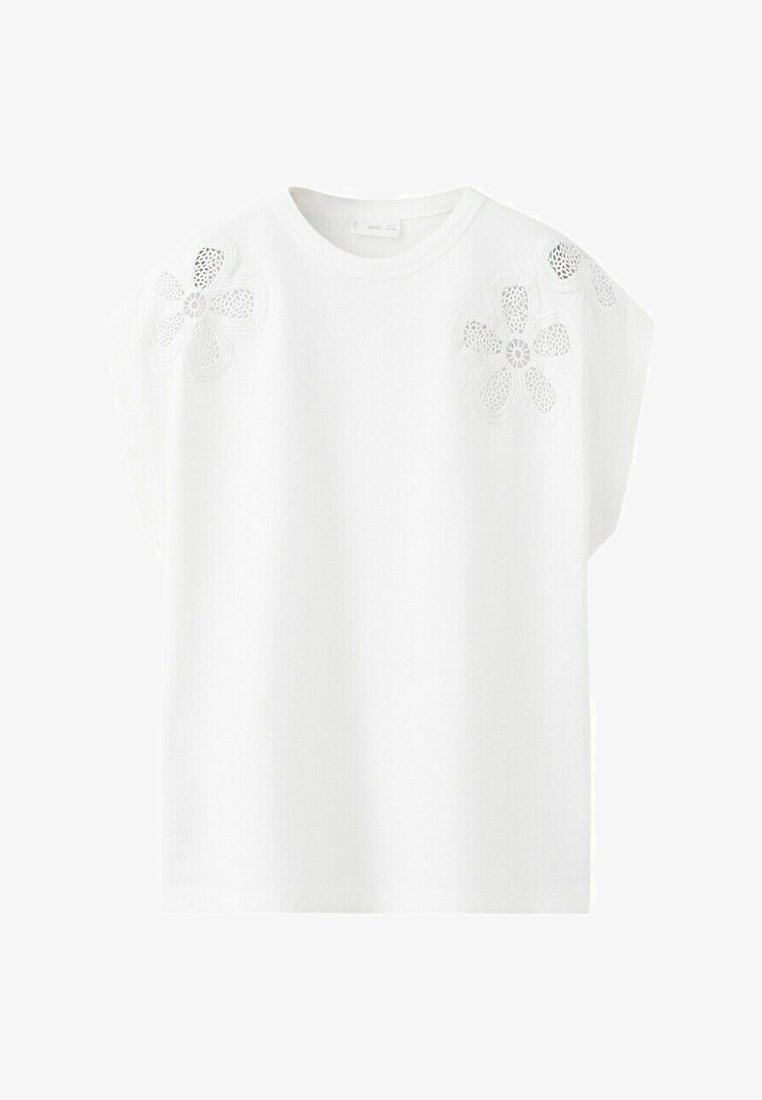 Haut blanc à manches courtes avec encolure ronde, orné de deux grandes applications de dentelle florale sur les épaules.